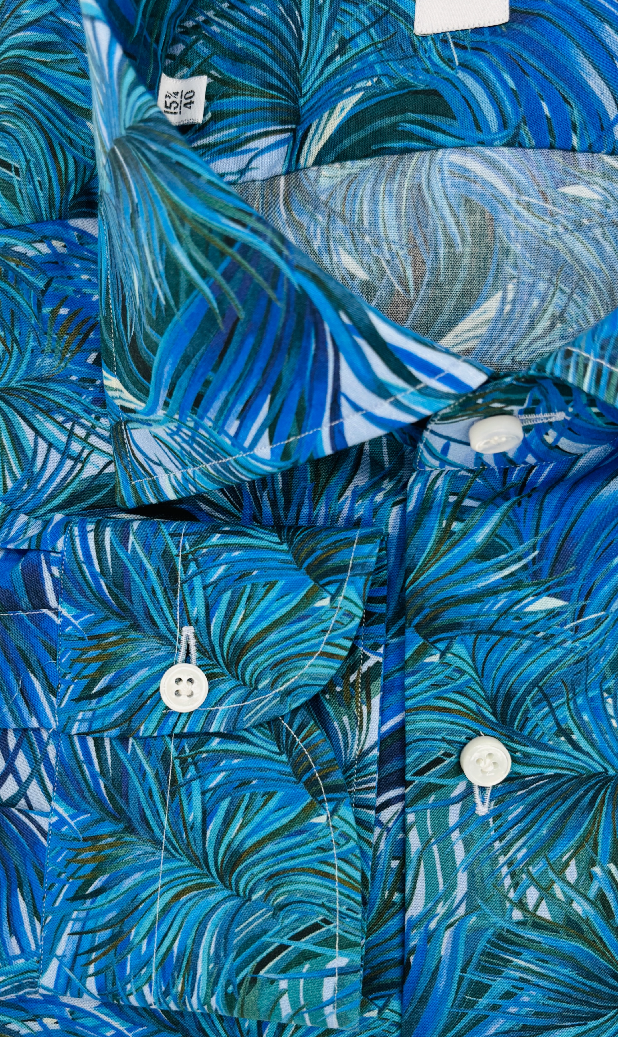 Manschetten und Perlmuttknöpfe des Slim-Fit-Hemds mit blauen Palmen Muster, gefertigt aus ägyptischer Baumwolle in Italien.
