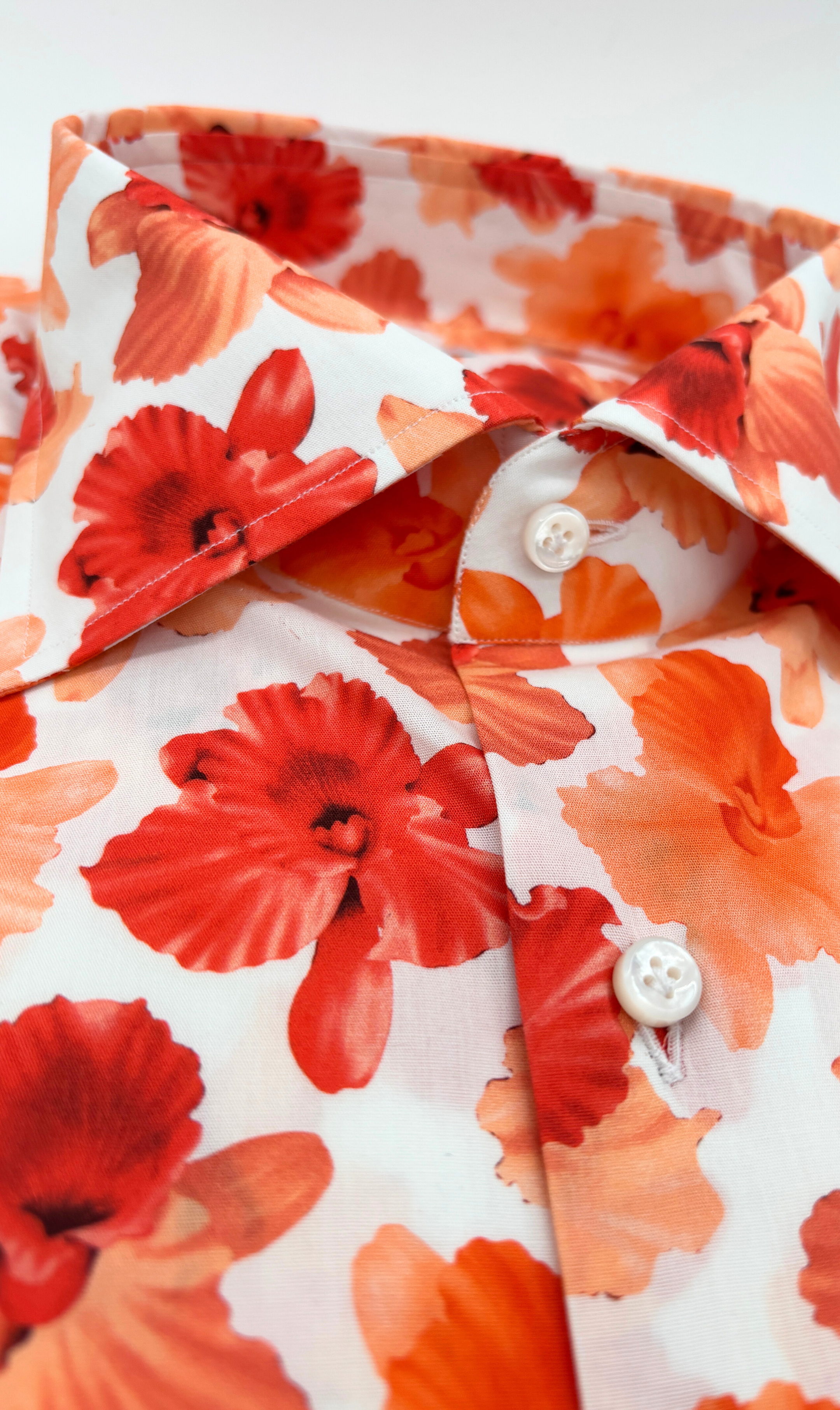 Detailansicht des Softcollar-Kragens und der runden Manschetten des nachhaltigen Herrenhemds mit orangenem Blumen-Muster.